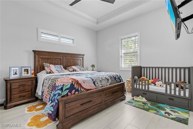 bedroom featuring crown molding, a raised ceiling, and ceiling fan