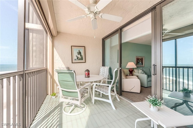 sunroom / solarium featuring a water view, a ceiling fan, and outdoor dining area