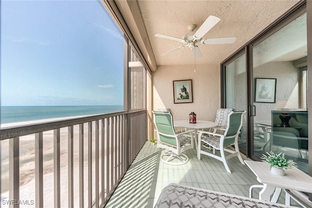 balcony with a water view, a ceiling fan, and outdoor dining area