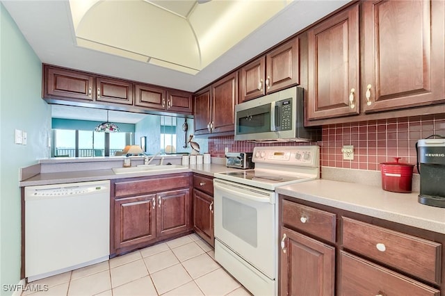 kitchen with white appliances, light countertops, tasteful backsplash, a sink, and light tile patterned floors