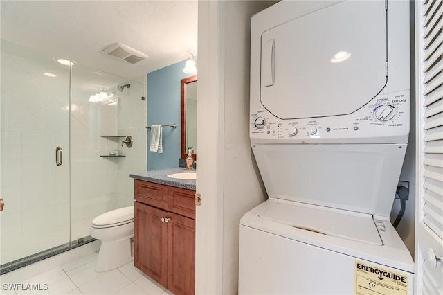 washroom with stacked washer / drying machine, visible vents, and light tile patterned floors