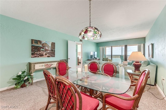 carpeted dining room featuring baseboards and a textured ceiling