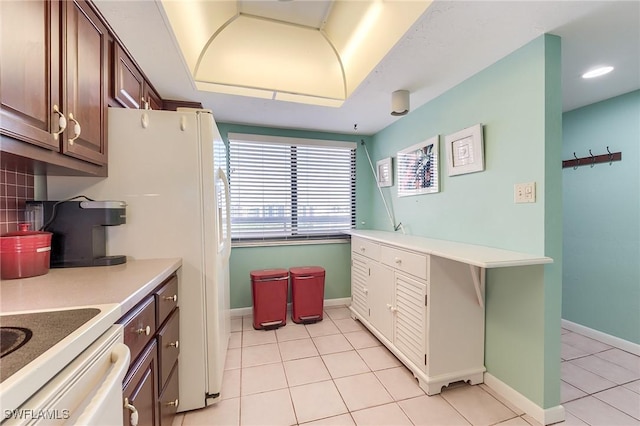 kitchen featuring light tile patterned floors, baseboards, and a tray ceiling