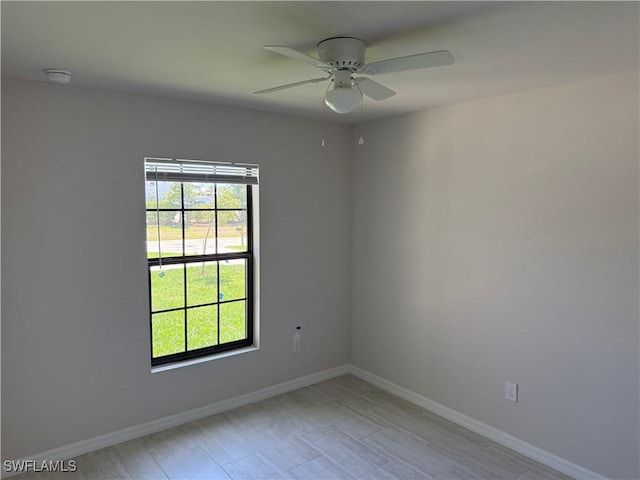 unfurnished room with baseboards, ceiling fan, and a wealth of natural light