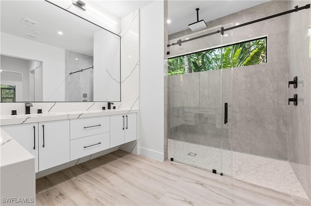 4693 13th Ave SW, Naples, FL 34116 - bathroom featuring a stall shower, double vanity, a sink, and wood finished floors