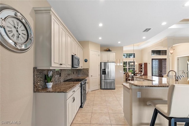 3824 SW 11th Pl, Cape Coral, FL 33914 - kitchen featuring backsplash, a kitchen bar, visible vents, dark stone countertops, and stainless steel appliances