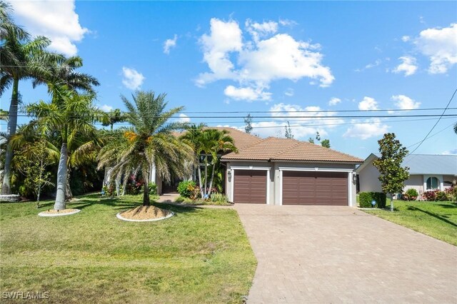3824 SW 11th Pl, Cape Coral, FL 33914 - view of front of home with driveway, an attached garage, a front yard, stucco siding, and a tiled roof