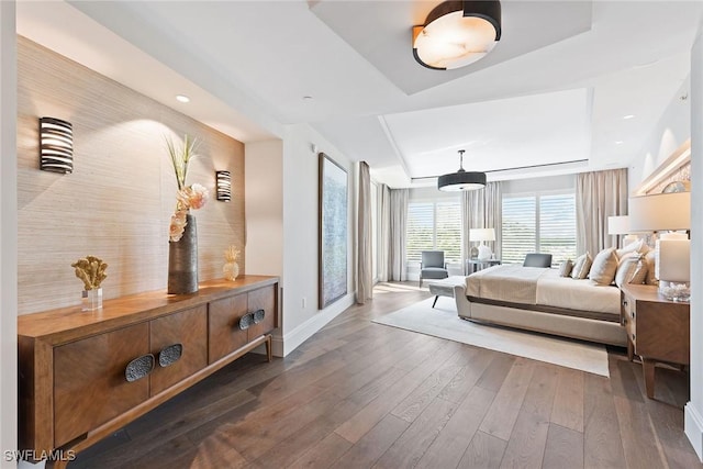 bedroom featuring a raised ceiling, baseboards, and hardwood / wood-style floors