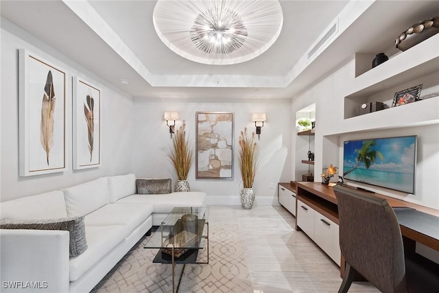 living room with baseboards, a tray ceiling, and visible vents