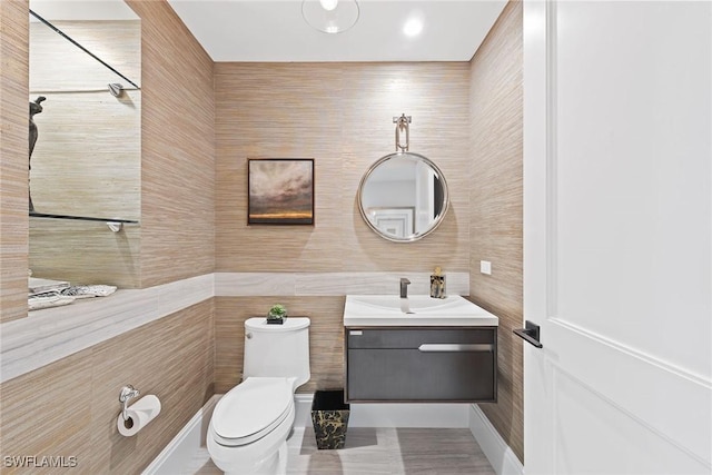 bathroom with toilet, tile walls, and vanity