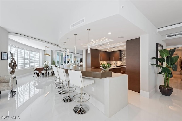 kitchen with a breakfast bar, dark brown cabinetry, visible vents, modern cabinets, and light tile patterned flooring