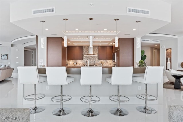 kitchen featuring a kitchen breakfast bar, visible vents, and wall chimney exhaust hood