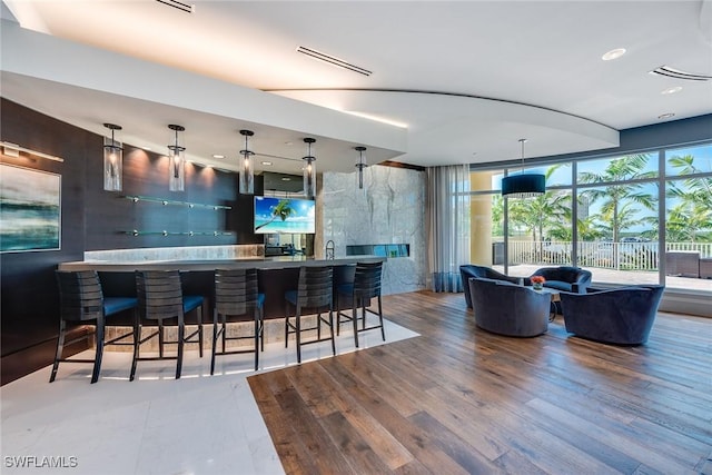kitchen featuring a breakfast bar area, wood finished floors, visible vents, decorative light fixtures, and recessed lighting
