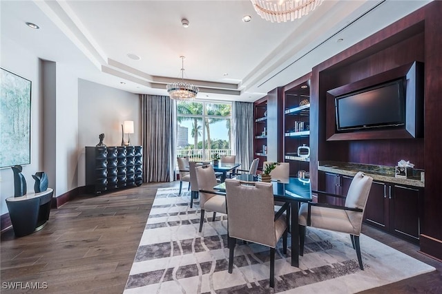 dining area with wood finished floors, recessed lighting, an inviting chandelier, a raised ceiling, and baseboards
