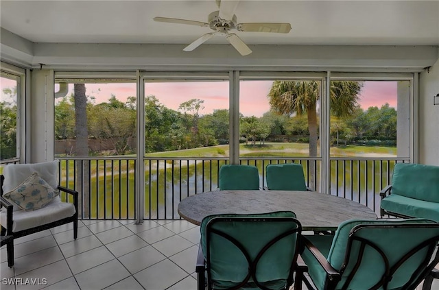 sunroom / solarium featuring ceiling fan and a water view
