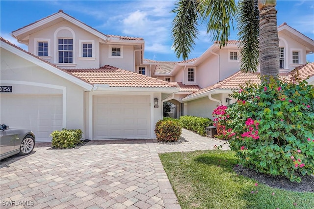 view of front of property with cooling unit, a tiled roof, stucco siding, and decorative driveway