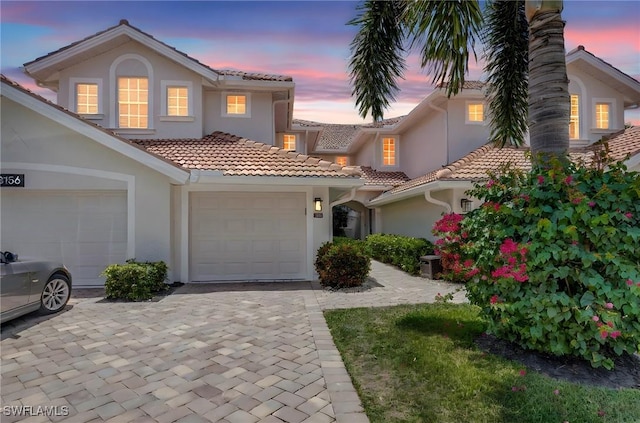 view of front of house featuring stucco siding, a tiled roof, and decorative driveway