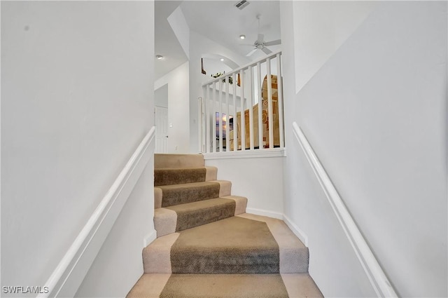 stairs featuring a ceiling fan, carpet, and a towering ceiling