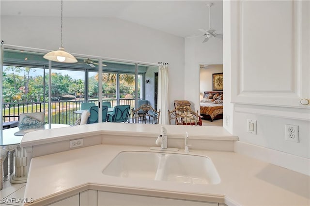 kitchen featuring a sink, lofted ceiling, pendant lighting, light countertops, and a ceiling fan