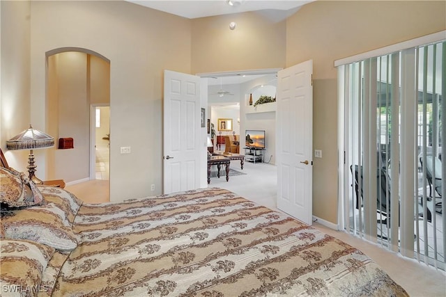 carpeted bedroom featuring a towering ceiling and arched walkways