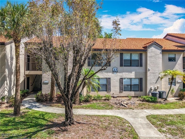 2178 Arbour Walk Cir Unit 2322, Naples, FL 34109 - view of front of house featuring stucco siding, stairway, a tile roof, and central AC unit