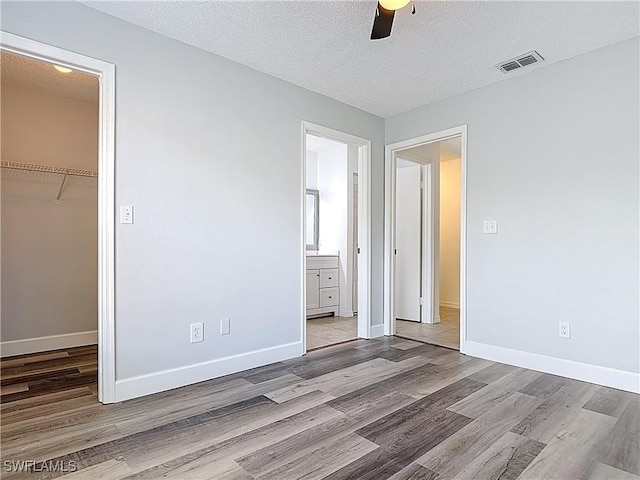 2178 Arbour Walk Cir Unit 2322, Naples, FL 34109 - unfurnished bedroom with wood finished floors, a spacious closet, baseboards, a closet, and a textured ceiling