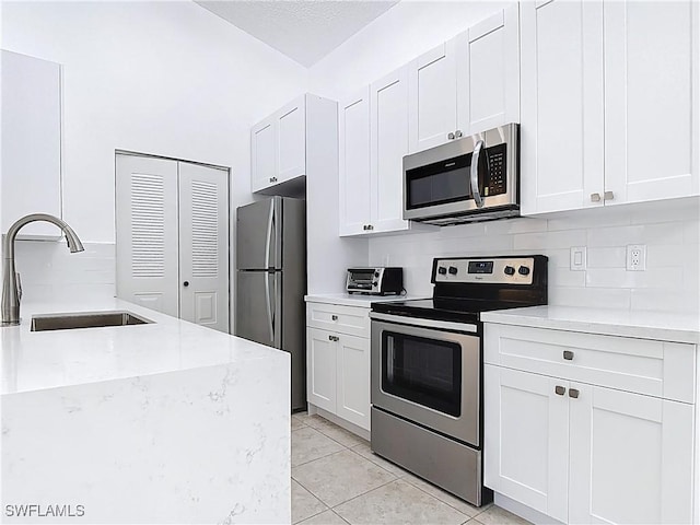 2178 Arbour Walk Cir Unit 2322, Naples, FL 34109 - kitchen with stainless steel appliances, a sink, tasteful backsplash, light tile patterned flooring, and light stone countertops