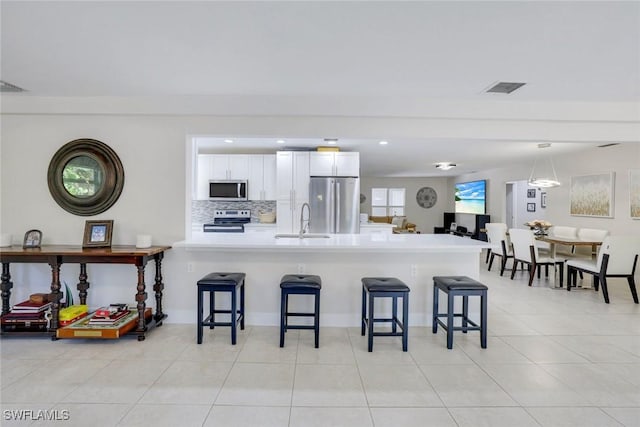 2855 66th St SW, Naples, FL 34105 - kitchen with appliances with stainless steel finishes, a breakfast bar, a peninsula, white cabinetry, and recessed lighting
