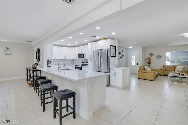 2855 66th St SW, Naples, FL 34105 - kitchen featuring appliances with stainless steel finishes, a peninsula, a sink, a breakfast bar, and light tile patterned floors