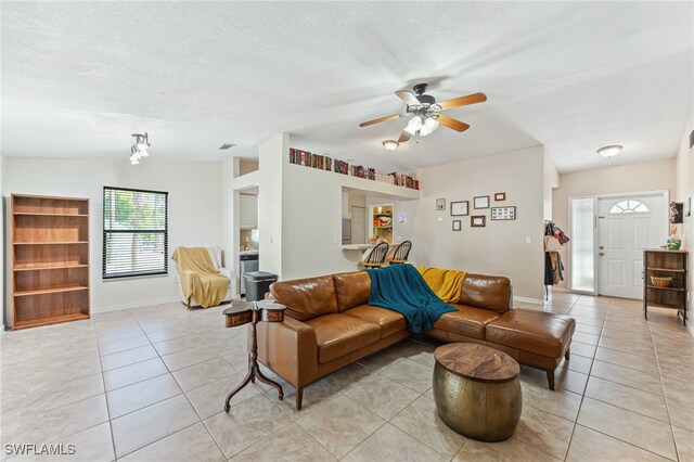 living area featuring baseboards, a textured ceiling, ceiling fan, and light tile patterned floors