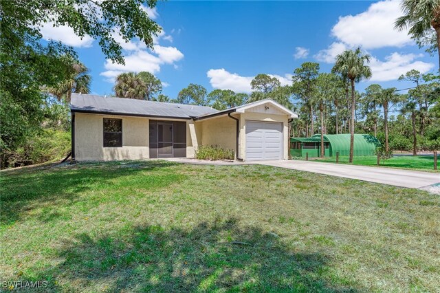 ranch-style home featuring metal roof, a garage, a front lawn, concrete driveway, and stucco siding