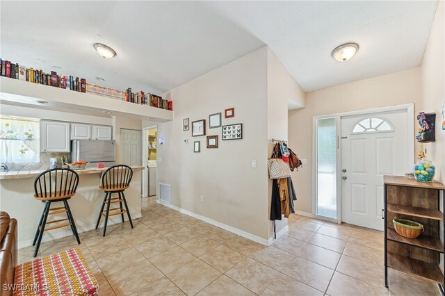 entryway with light tile patterned flooring, baseboards, visible vents, and a healthy amount of sunlight