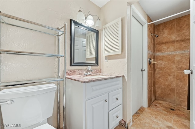 bathroom with vanity, a textured wall, and a tile shower