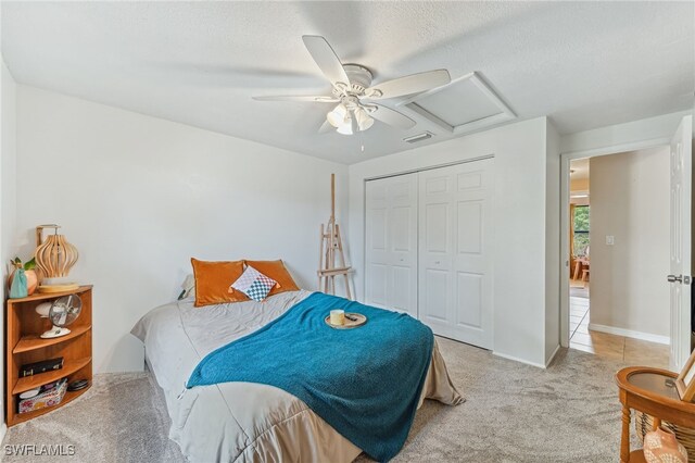 bedroom featuring a ceiling fan, attic access, visible vents, a closet, and light carpet