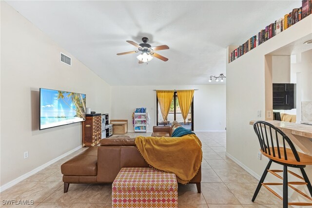 living area with visible vents, light tile patterned flooring, baseboards, ceiling fan, and vaulted ceiling