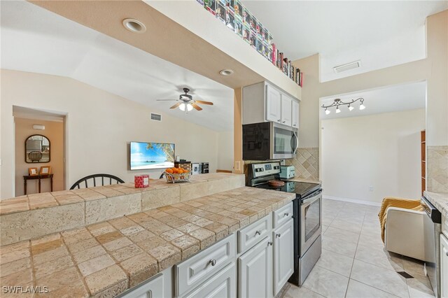 kitchen featuring stainless steel appliances, ceiling fan, vaulted ceiling, and visible vents