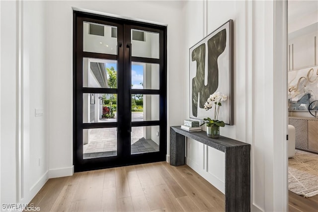 doorway featuring baseboards, french doors, and wood finished floors