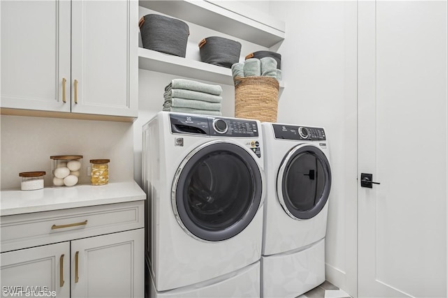clothes washing area with cabinet space and washer and dryer
