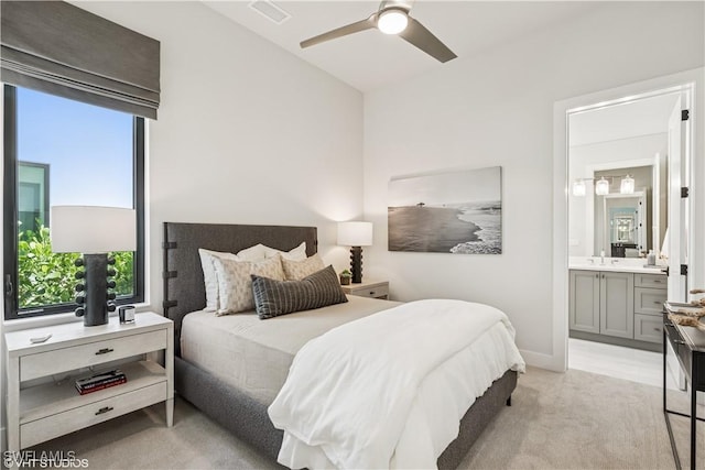 bedroom featuring ensuite bathroom, light colored carpet, ceiling fan, and visible vents