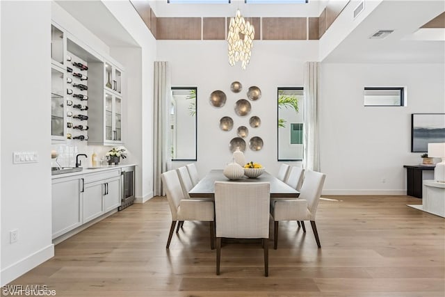 dining space with a notable chandelier, visible vents, baseboards, and light wood finished floors