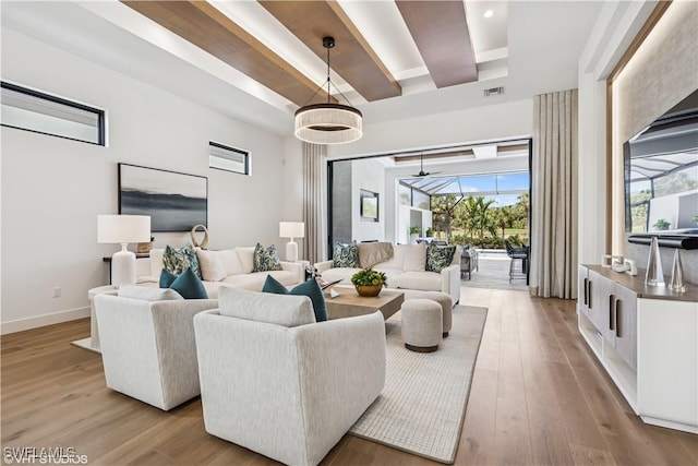 living area with plenty of natural light, a raised ceiling, wood finished floors, and visible vents