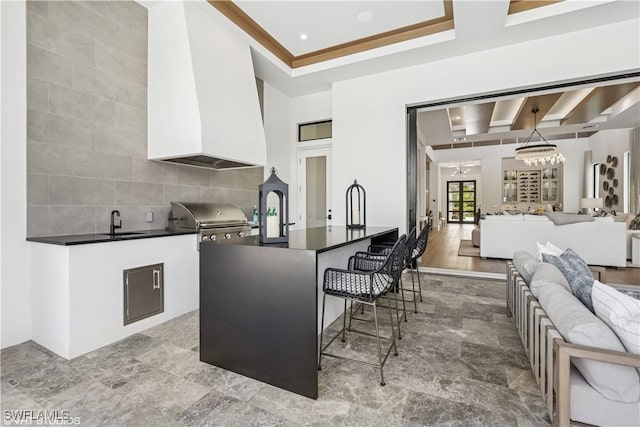 kitchen featuring a kitchen breakfast bar, dark countertops, a sink, white cabinets, and open floor plan