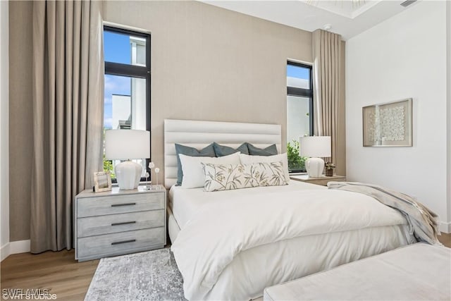 bedroom featuring baseboards, multiple windows, and wood finished floors
