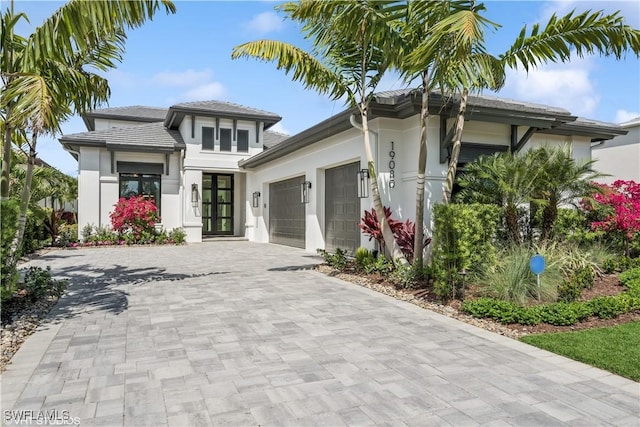prairie-style house featuring decorative driveway, a garage, stucco siding, and french doors