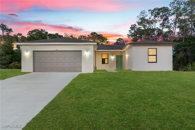 view of front of home with a yard, a garage, stucco siding, and driveway