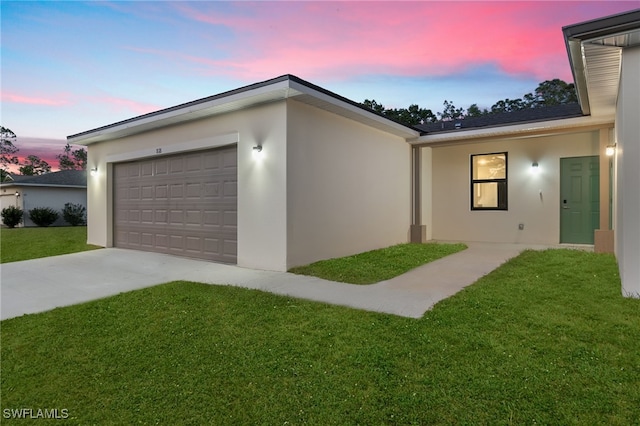 view of side of property featuring a yard, stucco siding, a garage, and concrete driveway