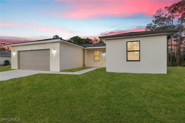 view of front of house with concrete driveway, stucco siding, a garage, and a front lawn