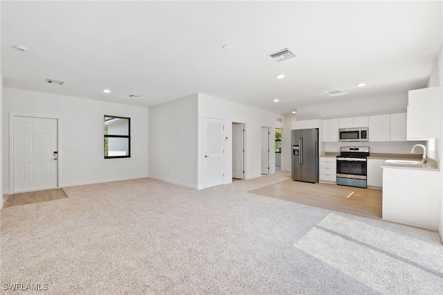 kitchen with light colored carpet, white cabinets, visible vents, and appliances with stainless steel finishes