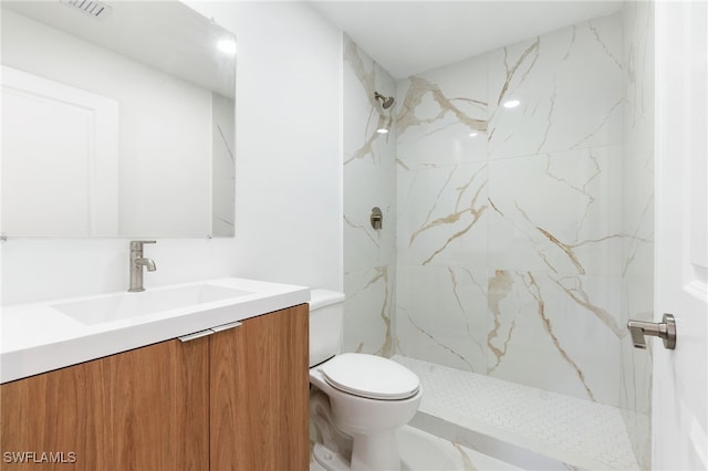 bathroom with vanity, toilet, a marble finish shower, and visible vents