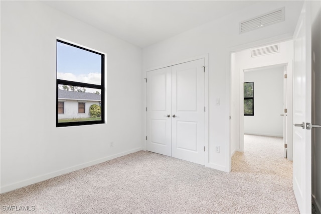 unfurnished bedroom featuring baseboards, a closet, visible vents, and carpet floors